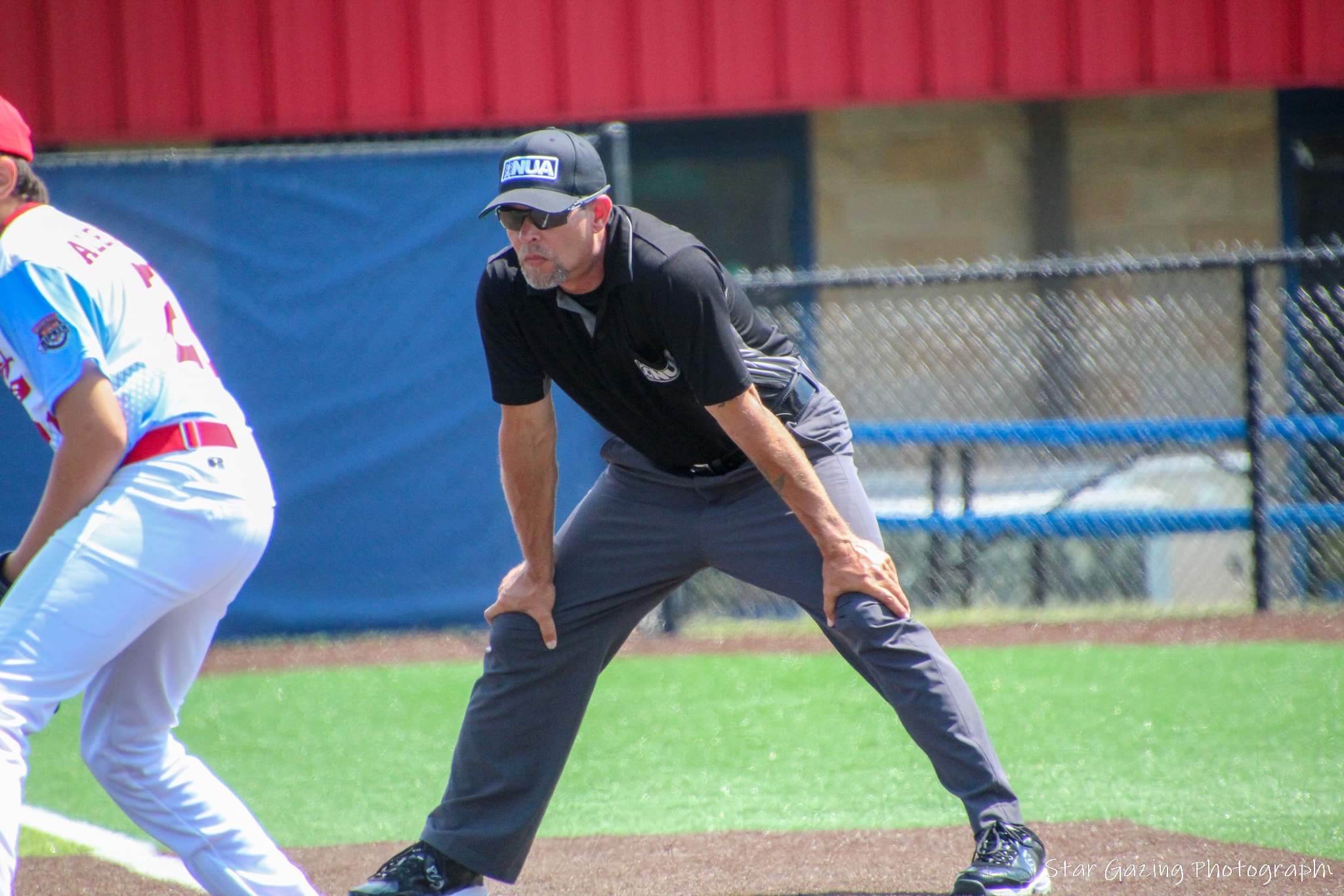 Umpire standing on field during youth baseball game.