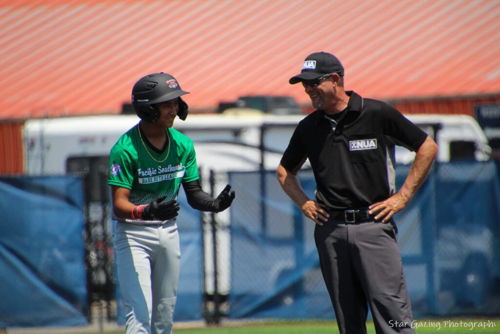 Umpire mentoring youth baseball player during game in Springfield, MO.