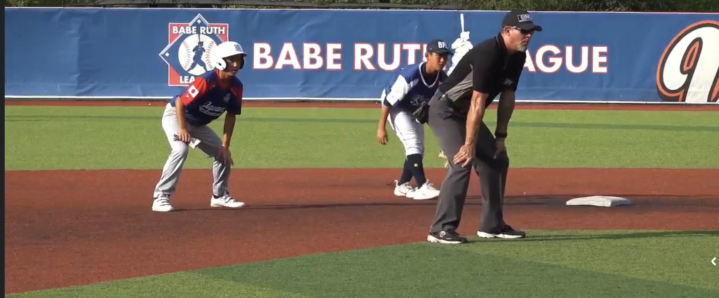 Baseball umpire making call at base during youth league game.