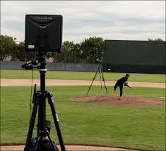TrackMan radar and camera system set up on baseball field capturing live pitching analytics.